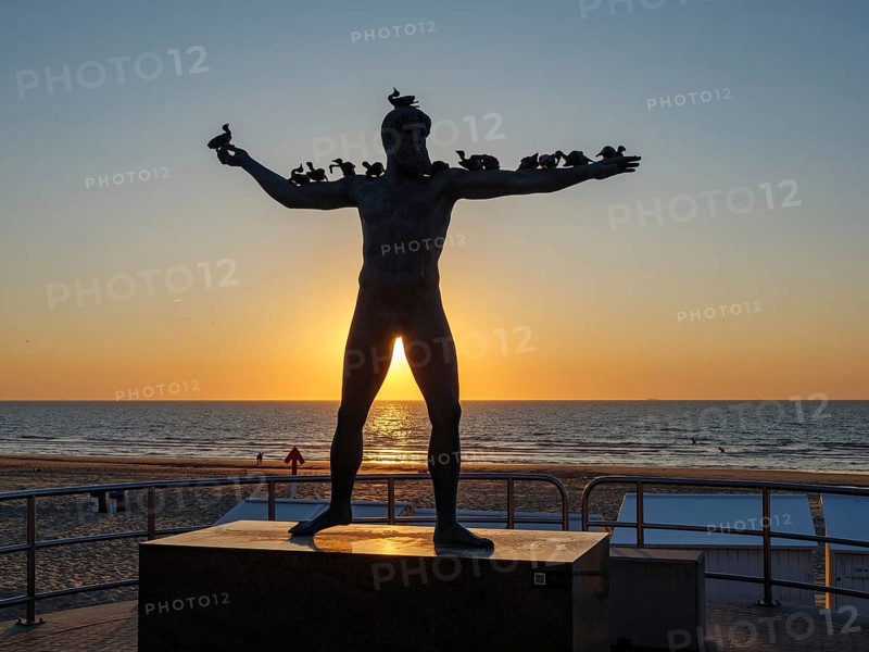 Sculpture on the beach at sunset with bird figures on the arms, silhouette against the light, sea in the background, De Haan, Flanders, Belgium, Europe