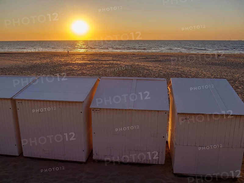 Sunset on the beach with white huts, empty sandy area and calm atmosphere, sea in the background, De Haan, Flanders, Belgium, Europe
