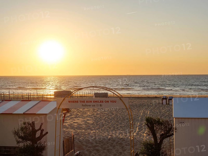 Sunset over the sea, beach with sand and an archway with lettering, quiet and peaceful atmosphere, De Haan, Flanders, Belgium, Europe