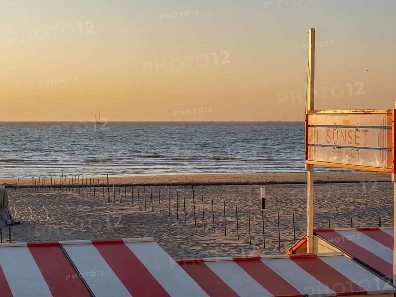 Sunset on the beach with a sign indicating the beach section, De Haan, Flanders, Belgium, Europe