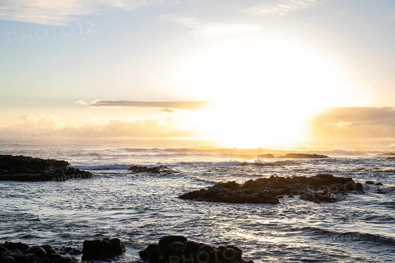 Sunrise over the sea with gentle waves. Sandy beach with lava rocks and blue water alternating with blue water. Island in the Indian Ocean, beach out of the blue, Trou d'Eau Douce, Mauritius, Africa