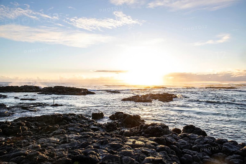 Sunrise over the sea with gentle waves. Sandy beach with lava rocks and blue water alternating with blue water. Island in the Indian Ocean, beach out of the blue, Trou d'Eau Douce, Mauritius, Africa