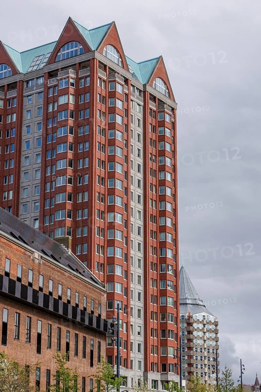 Tall modern residential building with red and grey facades and glass elements, rotterdam, the netherlands
