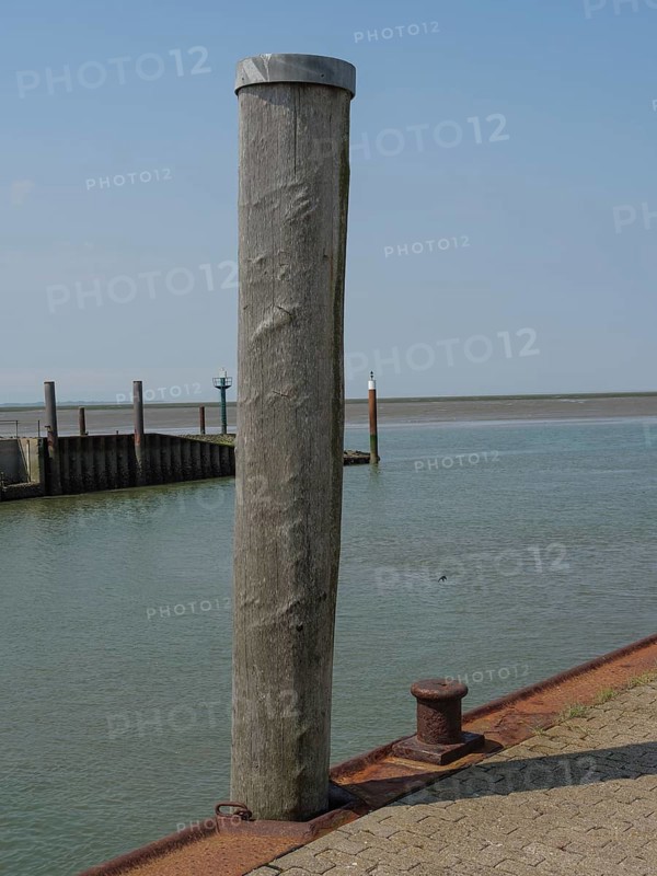 A single wooden pile at the edge of the harbour with a view of the calm sea and sky, hallig hooge, schleswig-holstein, germany
