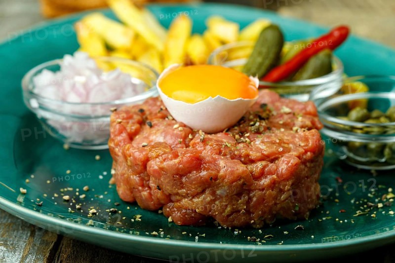 Steak tartare with open egg on wood