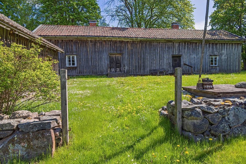 Rustic old farm with wooden house a water well and a gate by a stone wall in the swedish countryside, Suntak, Tidaholm, Sweden, Europe