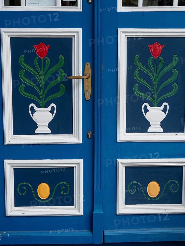 Close-up of a blue and white decorated door with tulip pattern and golden door handle, ahrenshoop, zingst, germany