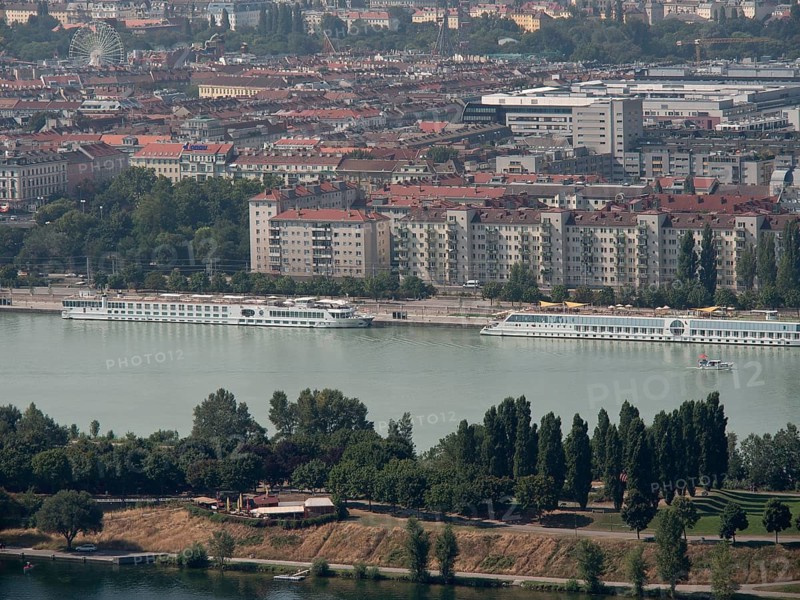 Panorama of a city by the river, lined with trees and large residential buildings in the background, Vienna, Austria, Europe