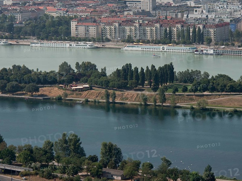 View of a riverside town with park-like areas, trees and residential buildings in the background, Vienna, Austria, Europe