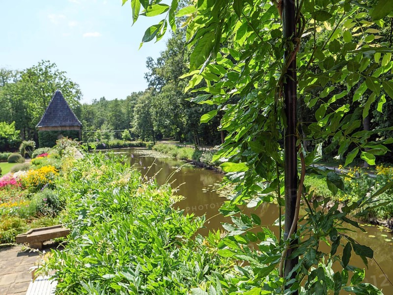 A garden with a river, colourful flowers and a pavilion in the background, ochtrup, münsterland, germany