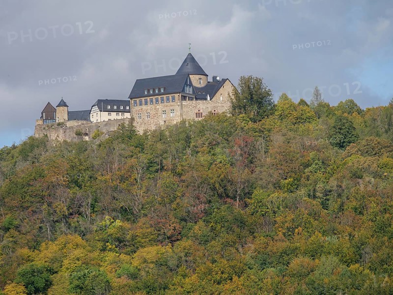 A medieval stone castle perched on a wooded hill surrounded by lush vegetation under a cloudy sky, Waldeck, Hesse, Germany, Europe