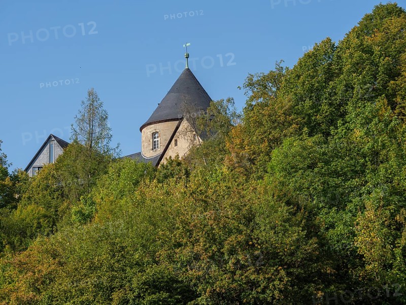 A medieval castle rises above green hills, partially hidden by trees, Waldeck, Hesse, Germany, Europe