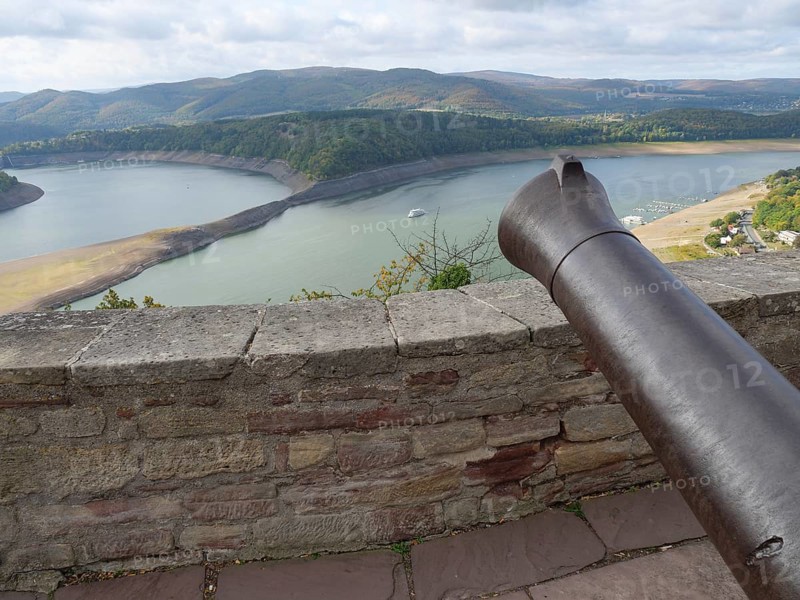 View from a stone wall with a cannon onto a lake surrounded by wooded hills under a cloudy sky, Waldeck, Hesse, Germany, Europe