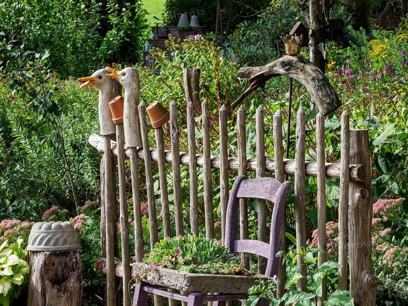 Wooden fence with duck statues and a purple chair in the garden surrounded by various plants and flowers, SChermbeck North Rhine-Westphalia, Germany, Europe