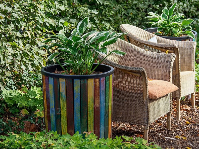 Large colourful flower pot with plants, next to it two rattan chairs in a green garden, SChermbeck North Rhine-Westphalia, Germany, Europe