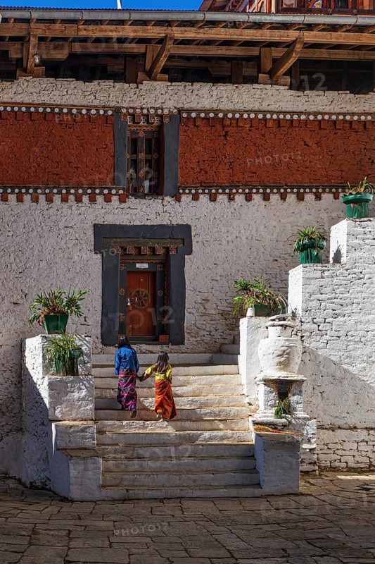Two undisclosed girls wearing colorful Kiras in the courtyard at Trongsa Dzong, one of the oldest Dzongs in Bhutan, Asia
