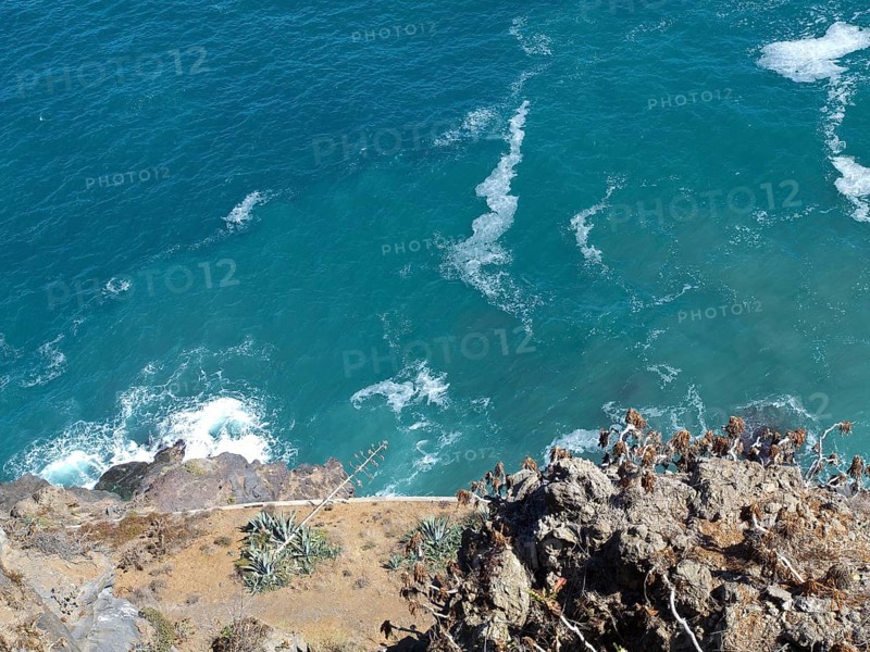 View from a cliff to the blue foaming sea and the rocky coast, Puerto de la cruz, tenerife, spain