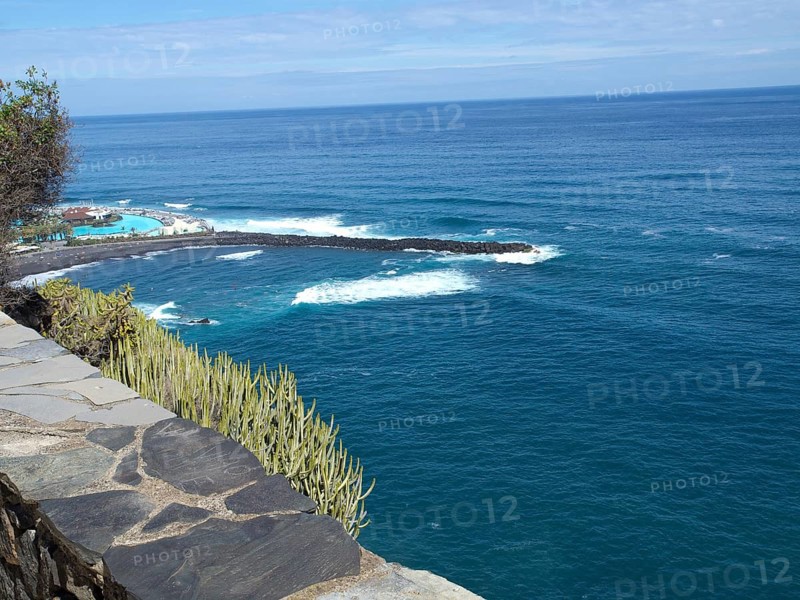 View of the vast sea and the waves lapping against the shore under a blue sky, Puerto de la cruz, tenerife, spain