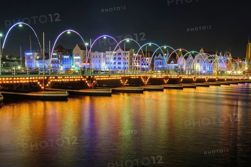 Night view of Queen Emma Bridge Queen Emma Bridge swing bridge Emma-Brug floating bridge with 16 pontoon boats Pontjesbrug pontoon bridge movable floating bridge over bay St Anna Bay Sint Annabaai in Willemstad behind landmark illuminated trading arcade houses in colonial style in Dutch Dutch Caribbean, Caribbean, Windward Islands, Netherlands Antilles, ABC Islands ABC Islands, Willemstad, Curaçao Curacao