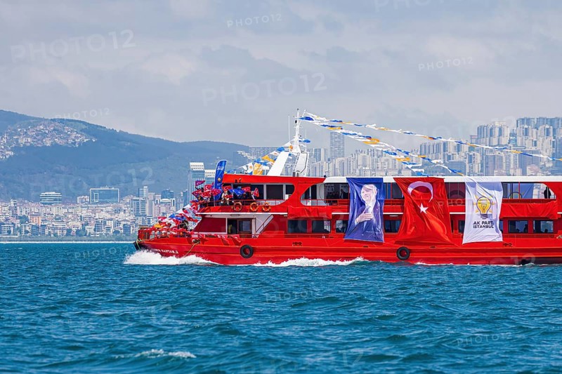 Supporters of the ruling AK party waving turkish flags on a red boat before presidential elections