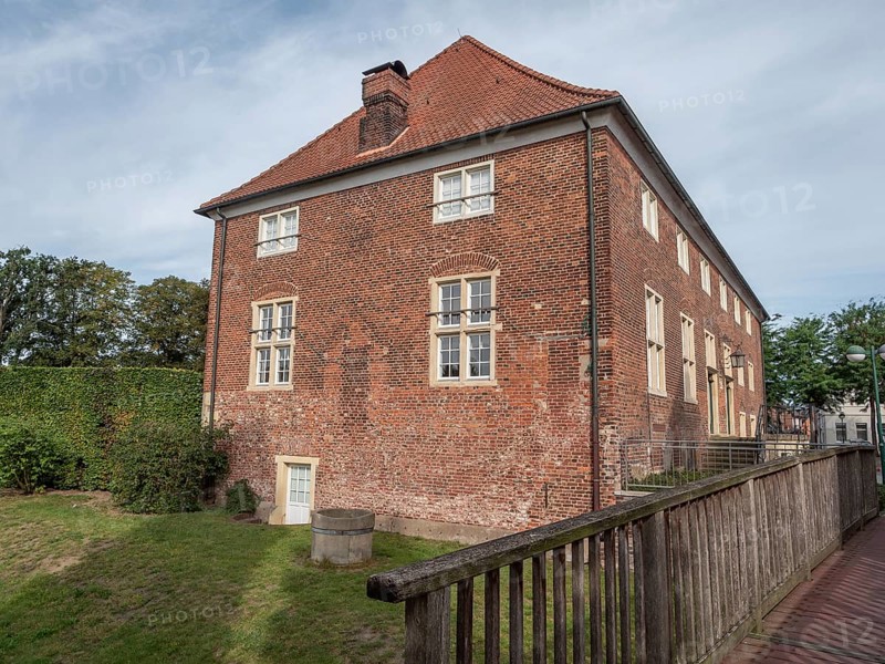 Brick building with gable roof and chimney, surrounded by a green meadow and a wooden fence, ramsdorf, münsterland, Germany, Europe