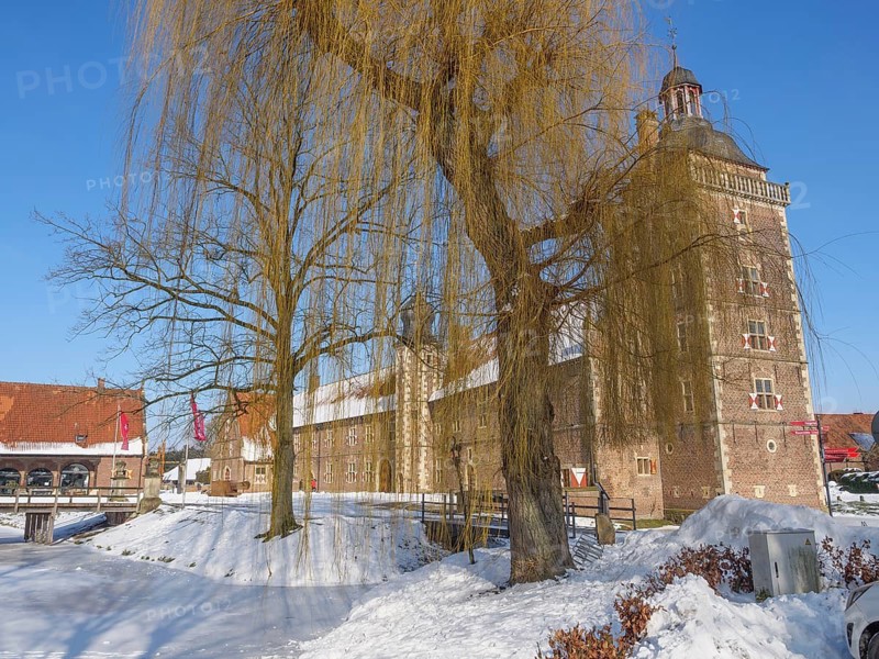 Castle in winter, next to a large willow tree, surrounded by snow and a clear blue sky, Raesfeld, münsterland, Germany, Europe