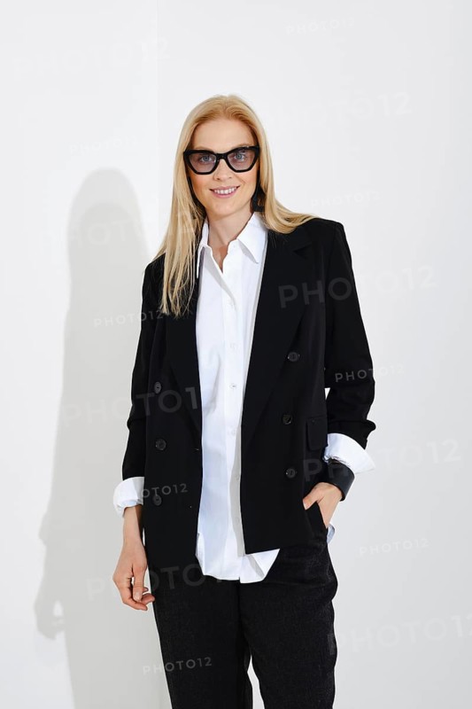 Medium closeup studio portrait of cute blonde woman in white shirt, black jacket and trousers