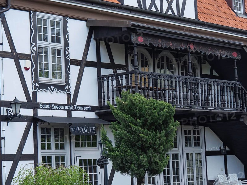 Detailed view of a half-timbered house with an ornately decorated balcony, large windows and green plants, Gdansk, Poland, Europe