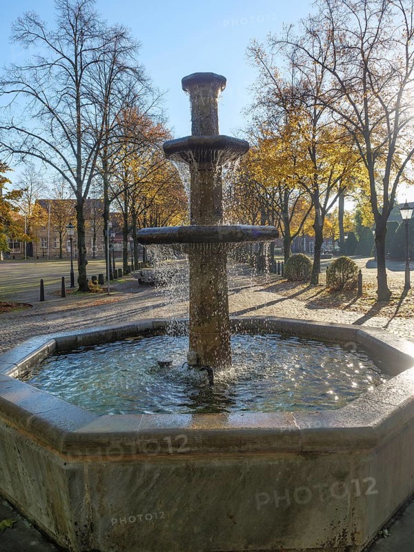 The water fountain, surrounded by autumn trees in the sunshine, creates a peaceful atmosphere, nottuln, münsterland, germany