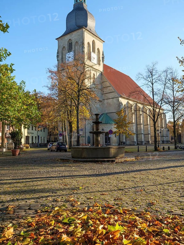 Church square in autumn, cobblestones covered with colourful leaves and church in the centre, nottuln, münsterland, germany