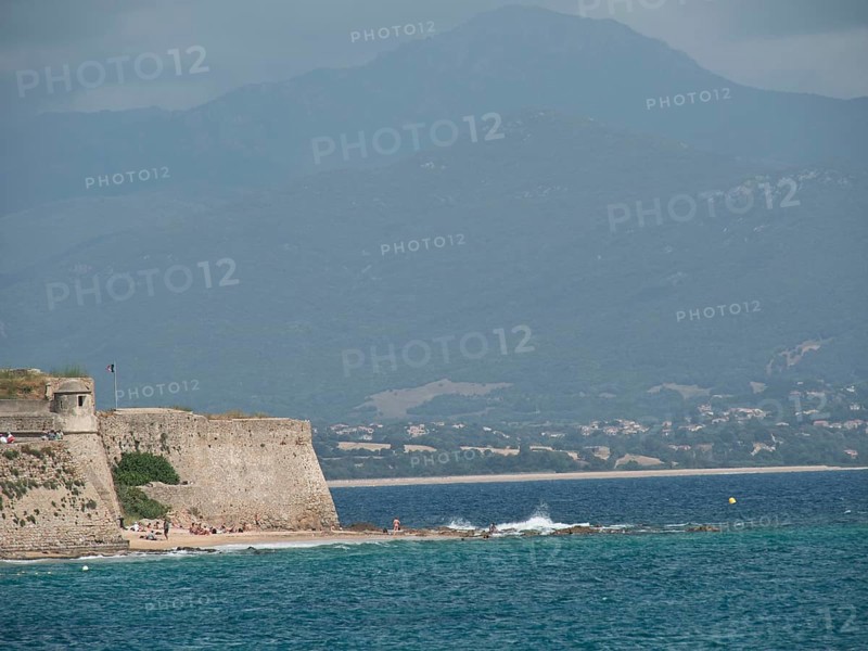Ancient fortress wall on the coast with a view of the sea and cloudy mountains in the background, ajaccio, corsica, france
