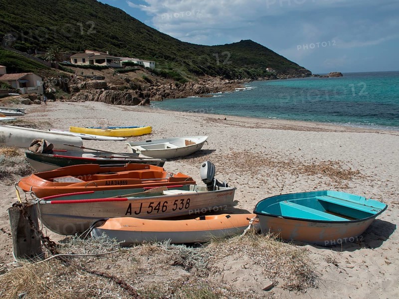 Several boats moored on the sandy beach in front of emerald green sea and green coastal hills, ajaccio, corsica, france