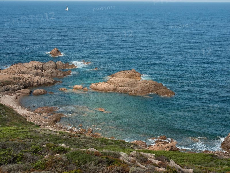 Clear blue water lapping various rocks along the coast under an expansive sky, ajaccio, corsica, france