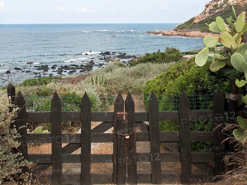 Black wooden gate leads to a coastal landscape with plants and sea views, ajaccio, corsica, france