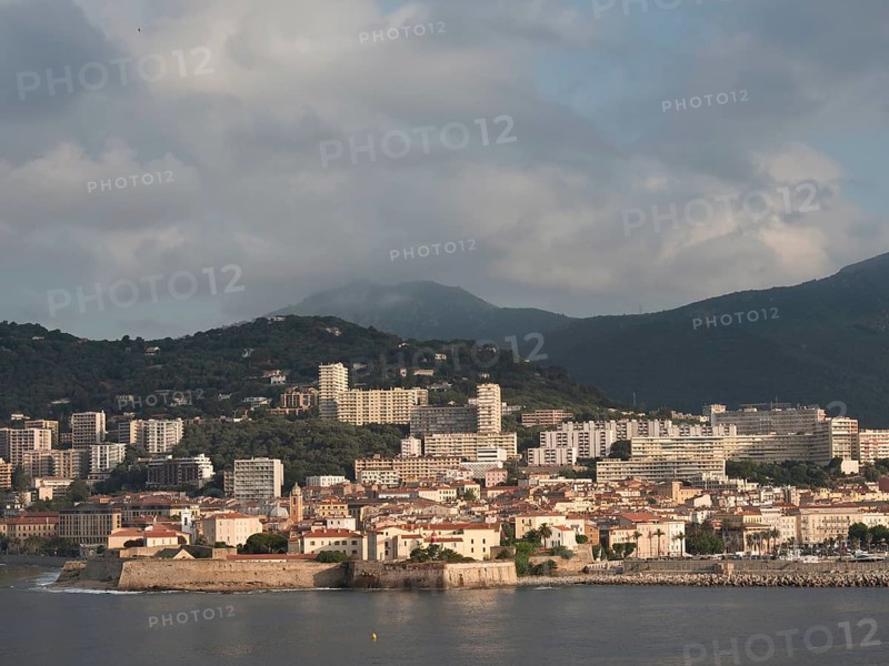 Coastal town with many buildings, mountains in the background and sunny sky, ajaccio, corsica, france
