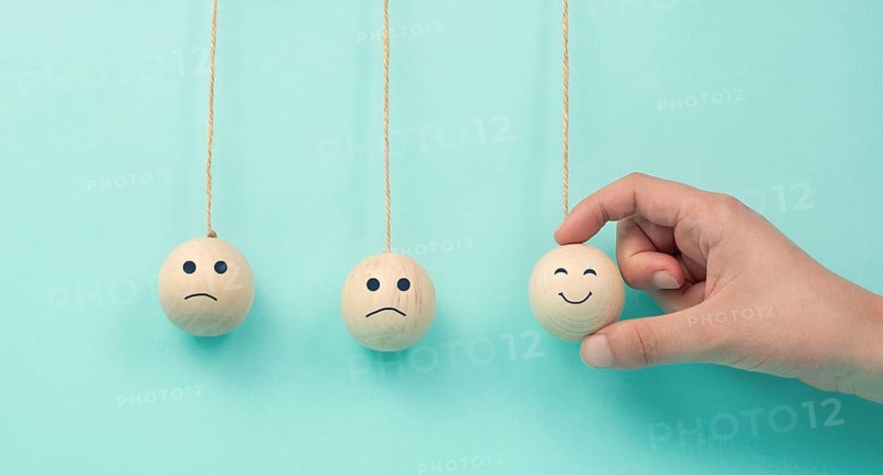 Happy smiling face spread happiness to sad faces, newton cradle concept, mental health and attitude, positive and negative mind, influence emotion, support and depression, pendulum balls