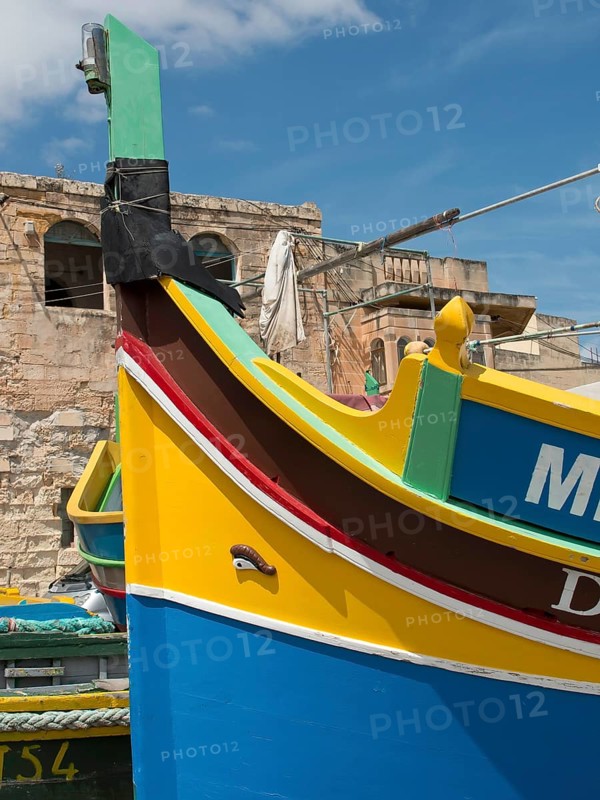 Colourful traditional boats in the harbour with historic stone walls in the background, marsaxlokk, mediterranean sea, malta