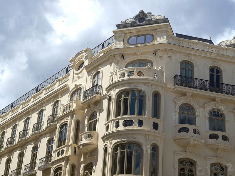 A historic building with ornate windows and wrought-iron railings under a cloudy sky, Malaga, Spain, Europe