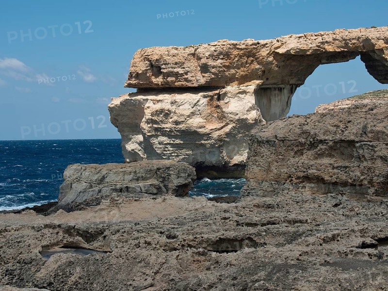Structure formed by a rocky arch on the coast with wild sea and a rocky rugged landscape, gozo, mediterranean sea, malta