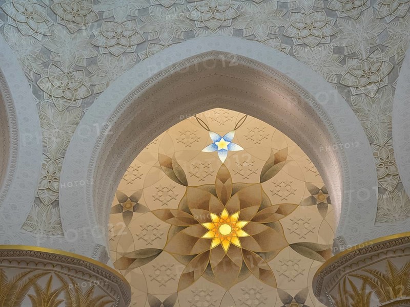 Ornate ceiling with intricate patterns and symmetrical design illuminated by beams of light, abu dhabi, united arab emirates