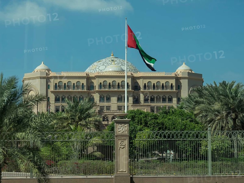An imposing palace with a waving flag and surrounded by palm trees, abu dhabi, united arab emirates