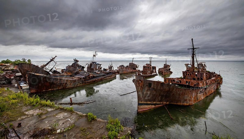 Dilapidated shipwrecks in the sea under a cloudy sky, gloomy and melancholic atmosphere, symbolic photo ship graveyard, AI generated, AI generated