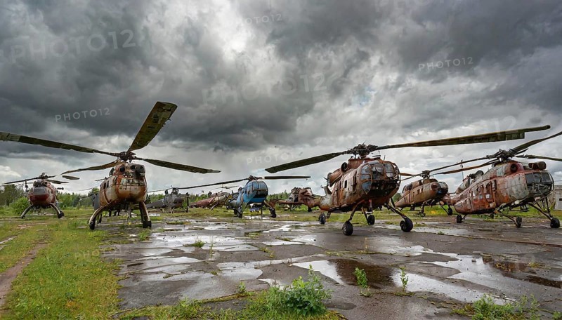 Several old, rusty helicopters are standing on an abandoned and overgrown area under an overcast sky, symbol photo, AI generated, AI generated