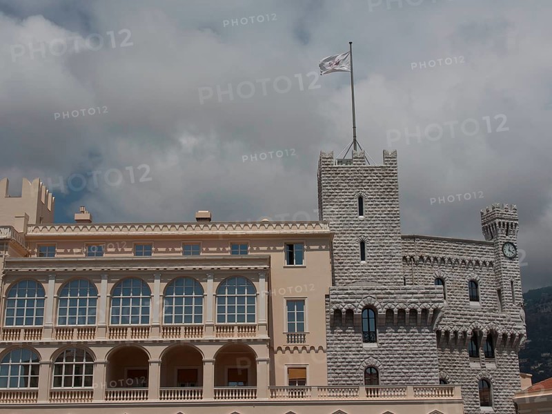 Historic castle with towers and waving flag in front of a cloudy sky, monte carlo, monaco, france