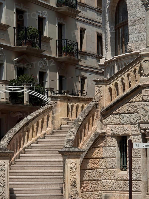 Stone staircase with ornate balustrade in front of historic buildings with balconies and ornate facades, monte carlo, monaco, france