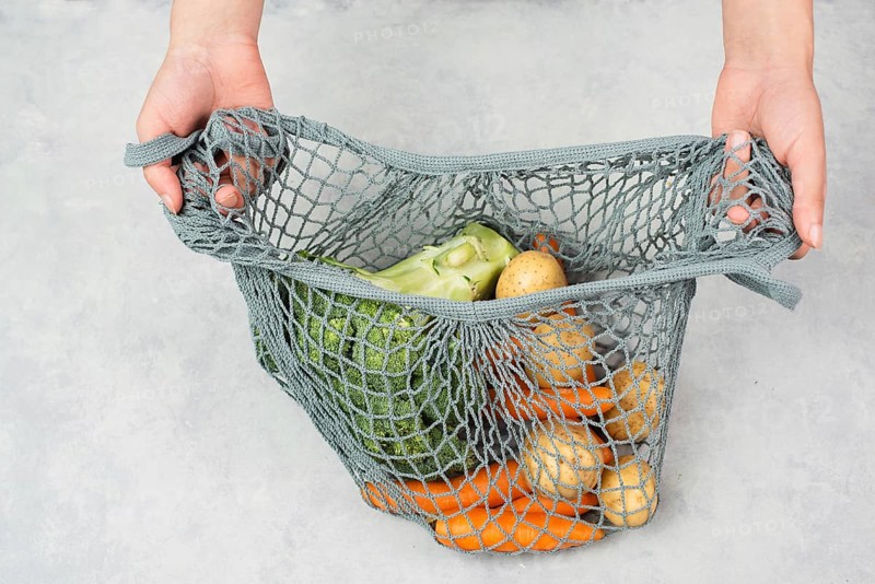 Mesh bag with vegetables, shopping grocery, healthy food ingredients, potato, broccoli and carrots, zero waste