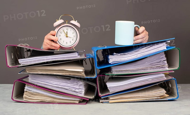 Exhausted tired woman with coffee and alarm clock, pile of file folders, burnout, stress and overworked, pressure at work