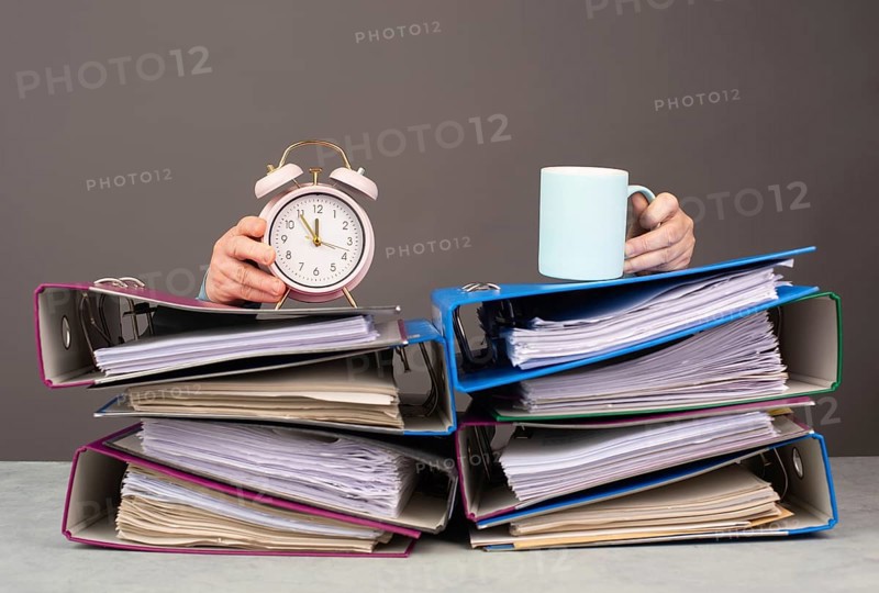 Exhausted tired woman with coffee and alarm clock, pile of file folders, burnout, stress and overworked, pressure at work
