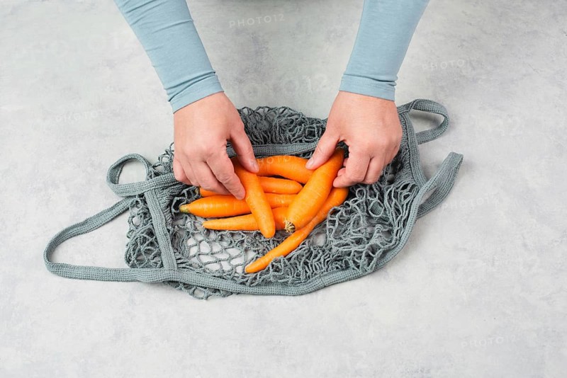 Unpack fresh carrots from a reusable grocery mesh bag, vegetables from the market, healthy food and zero waste