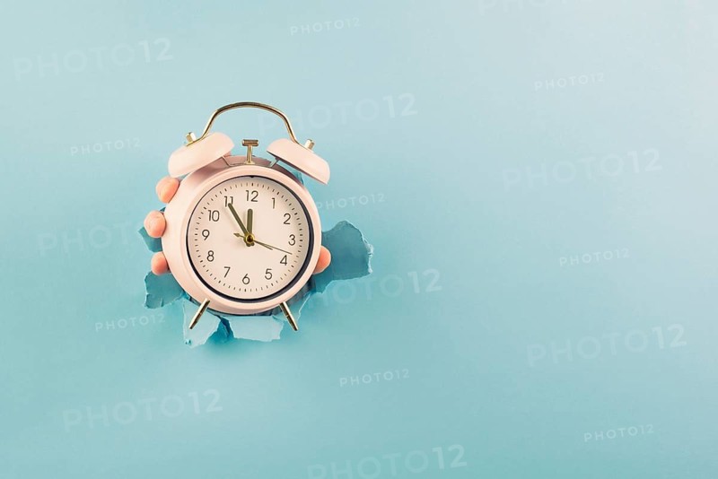 Hand holding alarm clock, torn paper hole, time management, reminder and planning, finish a deadline, timetable and stress, countdown